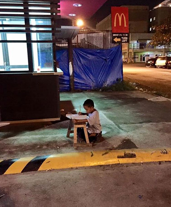 Este niño indigente hace los deberes en la calle a la luz de un McDonalds