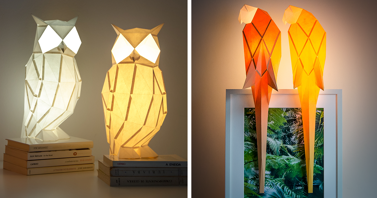 Lu00e1mparas de papel con diseu00f1o origami de bu00fahos y guacamayas iluminadas sobre libros y marco decorativo.