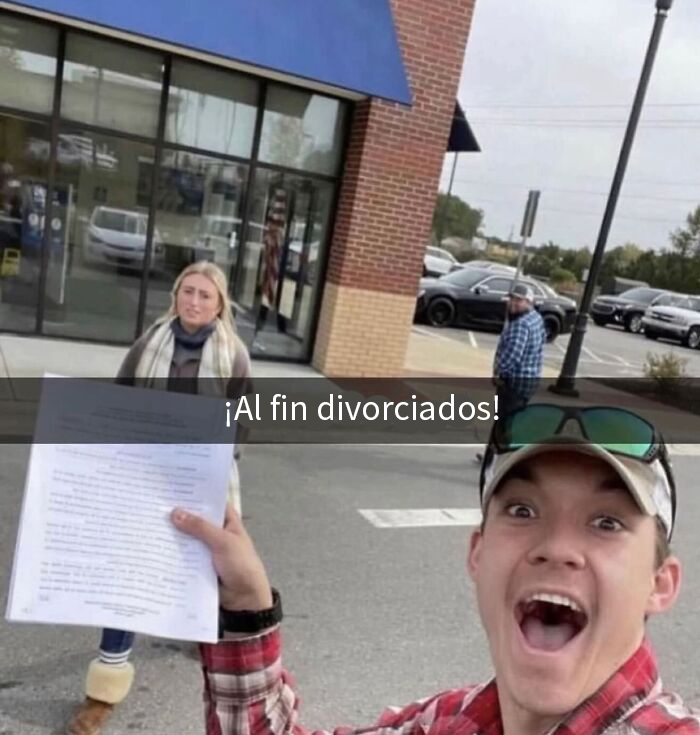 Joven sonriente sosteniendo un papel de divorcio con gesto sarcástico frente a una mujer en un aparcamiento.