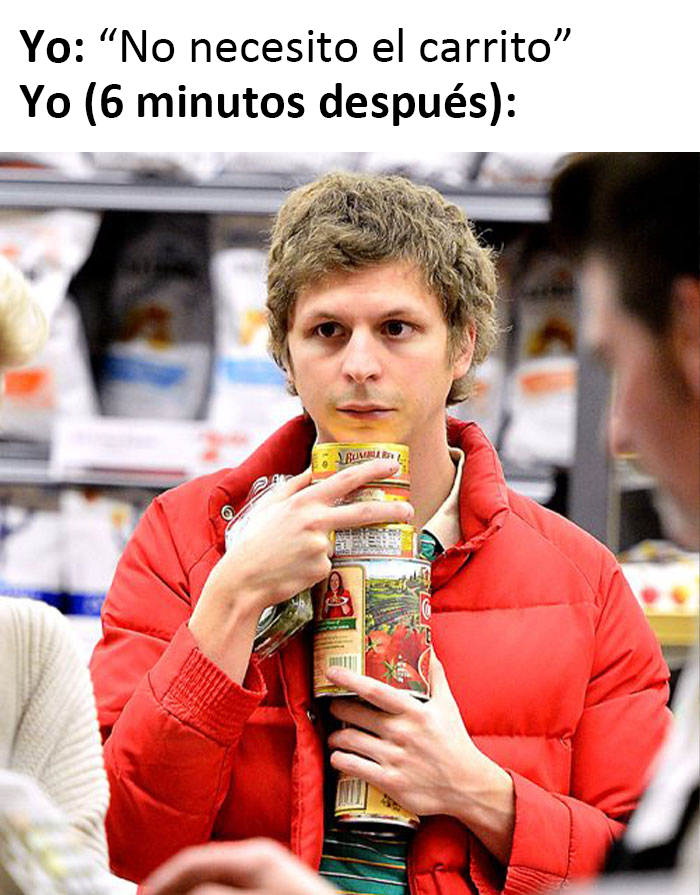 Persona sosteniendo varios productos de comida en el supermercado, sin carrito de compras.