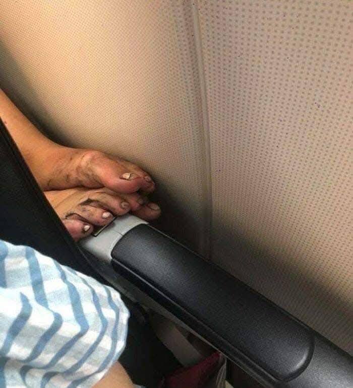 Pies sucios y uñas descuidadas en reposabrazos de asiento cerca de pared, ejemplo de personas que menos mal hicieron una foto.