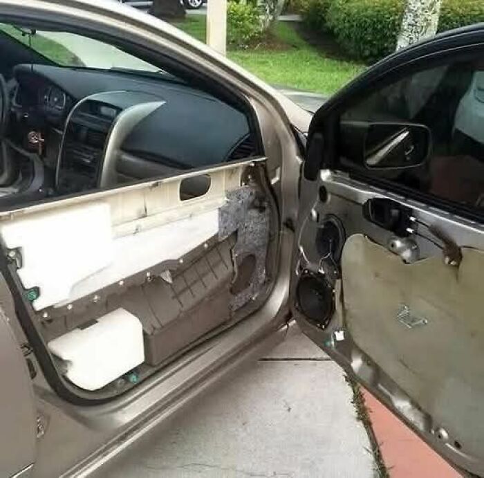 Puerta de coche sin panel interior, mostrando el mecanismo y mensaje de personas que menos mal hicieron una foto.