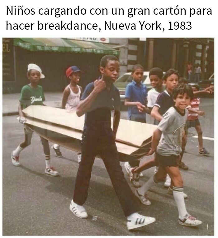 Niños en Nueva York en 1983 cargando un gran cartón para hacer breakdance, evocando nostalgia de los años 80.