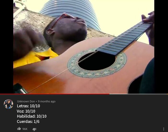 Hombre tocando guitarra con gafas rojas, captura de pantalla inusual con puntuación y comentarios en video.