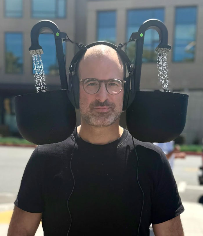 Hombre con auriculares y proyecto casero fallido de dos jarras con agua cayendo mientras se usan los auriculares.