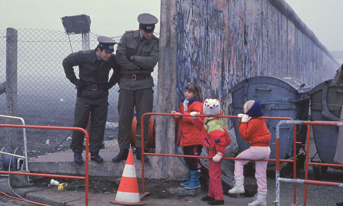 Escolares de Alemania Occidental se detienen a hablar con dos guardias fronterizos de Alemania Oriental junto a una abertura en el Muro de Berlín durante la caída del comunismo en Alemania Oriental en noviembre de 1989 (Foto: Stephen Jaffe)