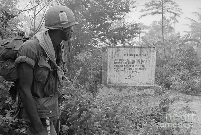 Un soldado negro de EE.UU. lee un mensaje dejado por el Việt Cộng durante la guerra de Vietnam: "Soldados negros de EE.UU., estáis cometiendo los mismos crímenes ignominiosos en Vietnam del Sur que el KKK está perpetrando contra vuestras familias en casa", 1970