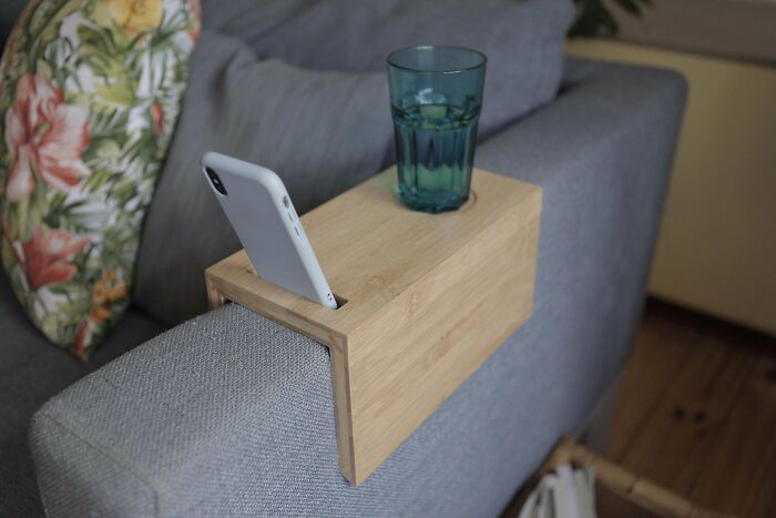 ¡Mi primer proyecto! Una bandeja para el brazo del sofá, con una ranura para el móvil y un pequeño espacio para un vaso o una taza. Hecho en madera laminada de bambú, con una tira de madera de haya reciclada en la ensambladura inferior. Se ve simple, pero tiene algunos detalles complejos