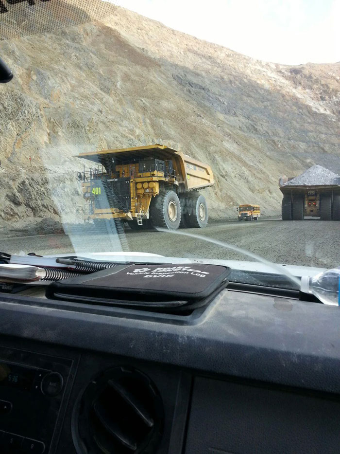 Un autobús escolar de tamaño normal junto a camiones mineros de transporte