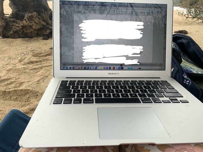 Mi madre está usando su portátil bajo la lluvia en la playa