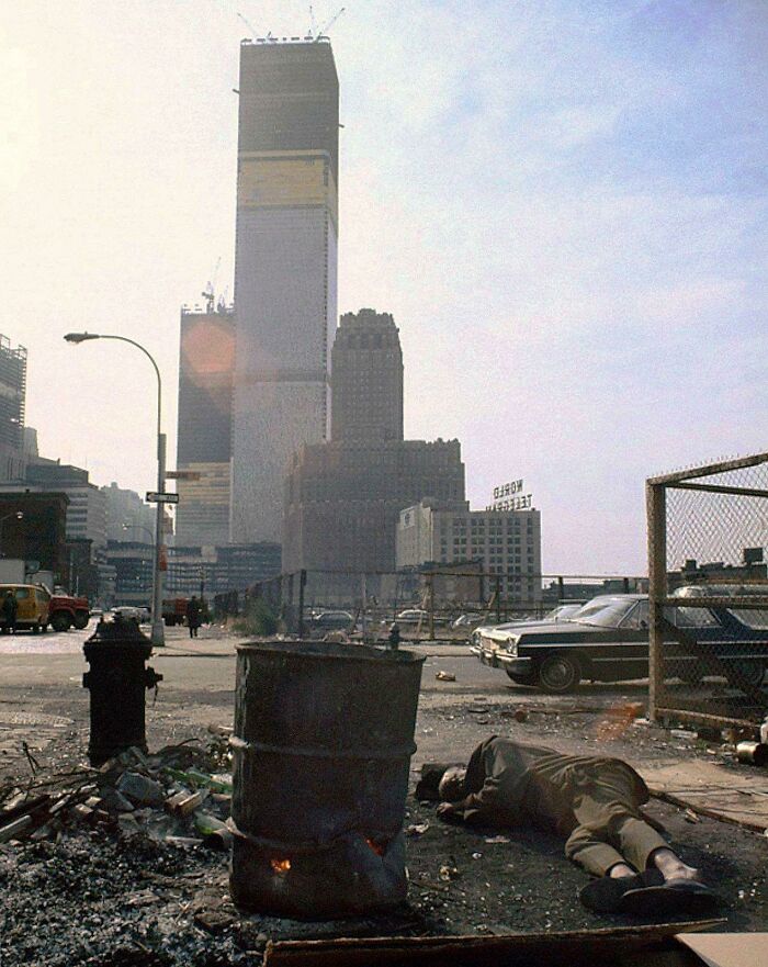 Un indigente duerme junto a un bote de 50 galones con madera en llamas frente al World Trade Center en construcción, Nueva York, 1970