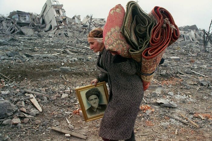 Una anciana abandona su casa con sólo un retrato de su marido y unas alfombras. Los soldados rusos le dieron sólo 5 minutos para hacer las maletas y marcharse antes de destruir su casa y todo lo que había en ella. Sus hijos y su marido ya estaban muertos. Lo había perdido todo. Mayo de 1995, Grozny