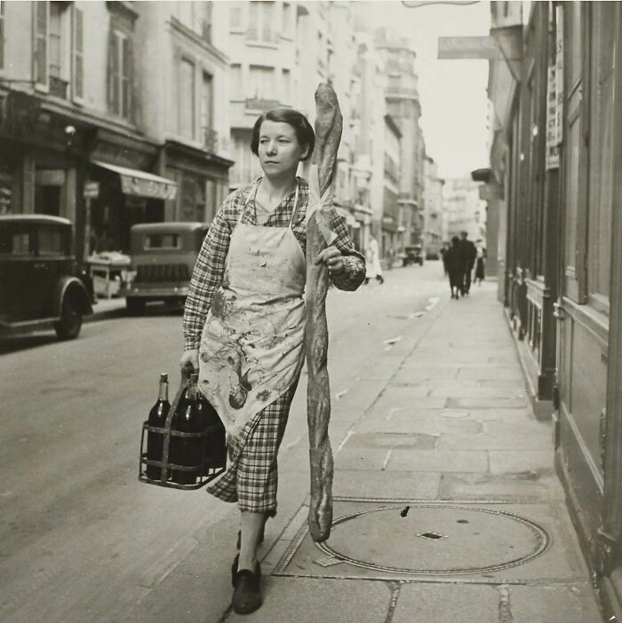 Una mujer francesa con su baguette y seis botellas de vino, París, Francia, 1945