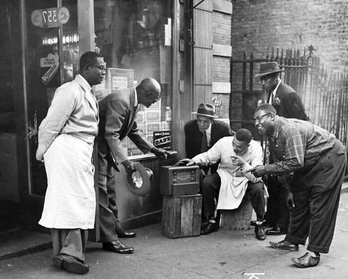 Hombres en Harlem se reúnen frente a una tienda para escuchar la radio, 1940