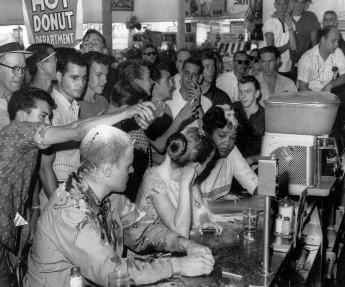 Una multitud vierte azúcar, ketchup y mostaza sobre las cabezas de John Salter, Joan Trumpauer y Anne Moody