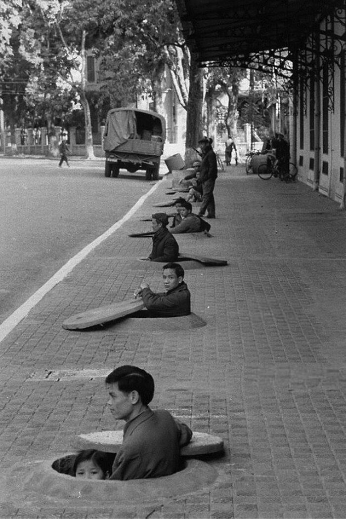 Los residentes de Hanoi esperan en refugios en las aceras durante una alerta de ataque aéreo. Hanoi, Vietnam del Norte, 1967