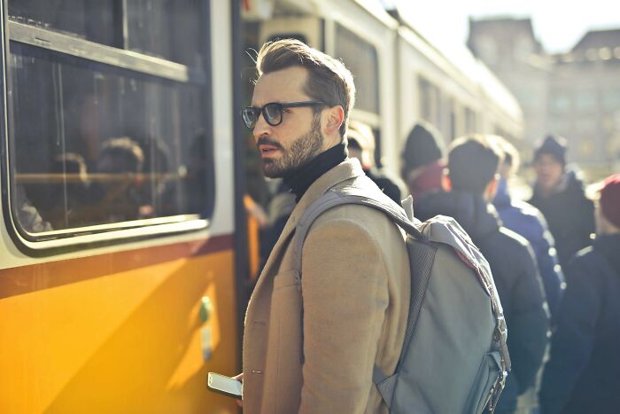 Hombre con mochila y gafas esperando transporte público, ilustrando conceptos de datos muy informativos sorprendentes.