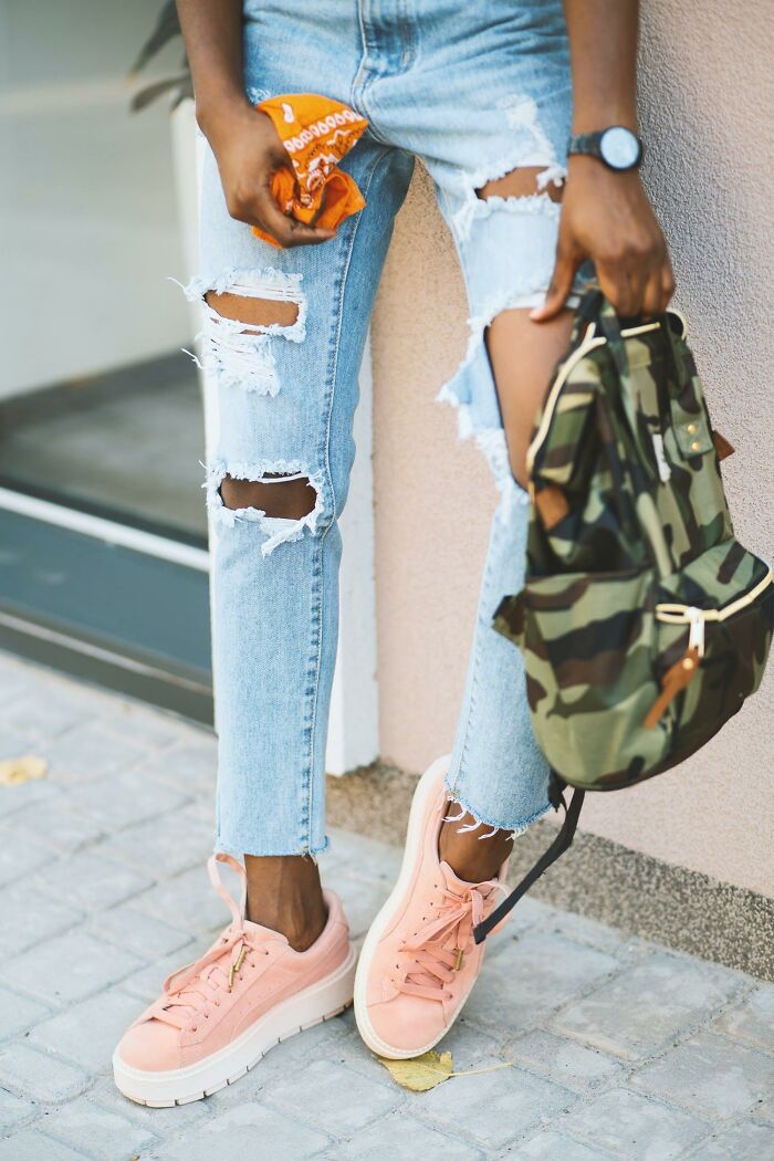 Piernas con pantalones rotos, zapatillas rosas y mochila camuflaje mostrando estilo urbano moderno datos muy informativos