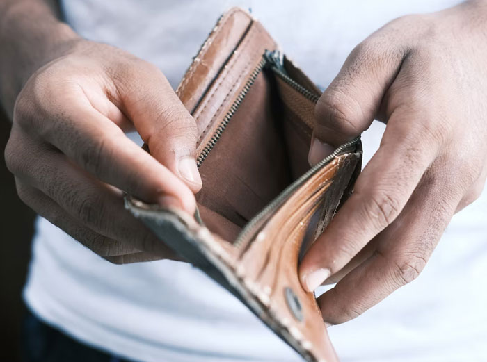 Manos abriendo cartera vacía mostrando interior sin dinero y datos muy informativos sorprendentes sobre finanzas personales.