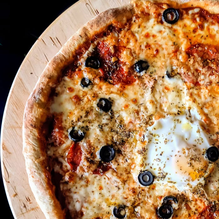 Pizza casera con queso, aceitunas negras y huevo, deliciosa comida acompañada de datos muy informativos y curiosos para conocer.