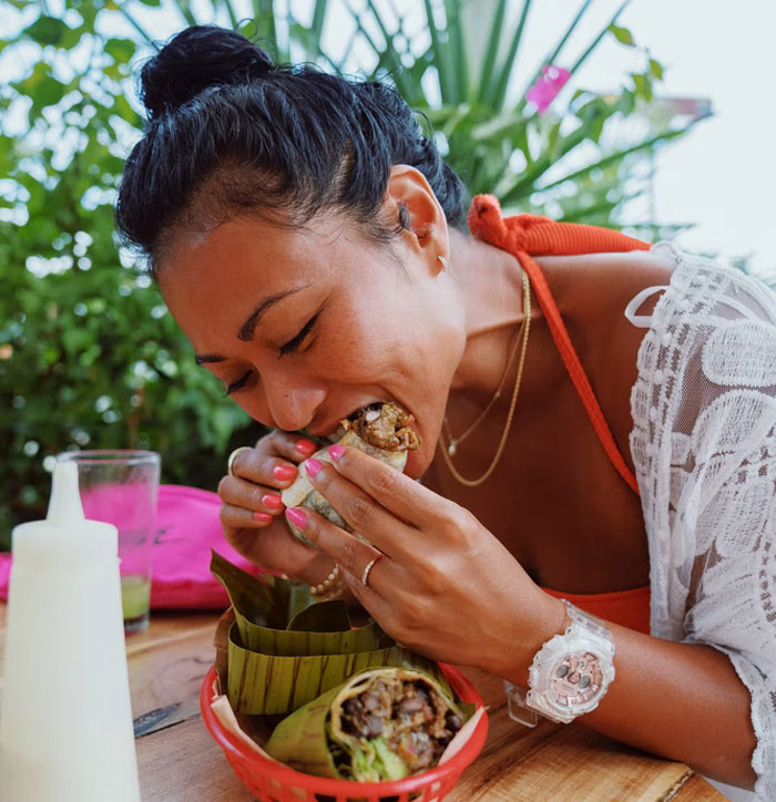 Mujer disfrutando una comida típica mientras descubre datos muy informativos que parecen casi ilegales.