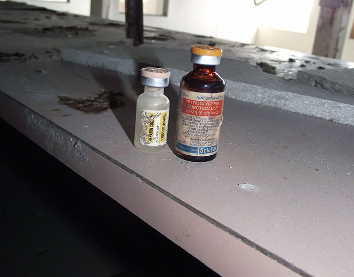 Dos frascos de medicamentos antiguos sobre una superficie polvorienta en un lugar abandonado, datos informativos curiosos.