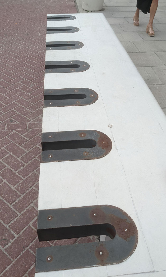 Banco de parque con extraños recortes. No creas que es para bicicletas, necesitarías una cadena muy larga para rodearlo todo