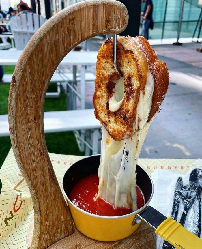 Una dona glaseada con queso a la parrilla colgando sobre sopa de tomate
