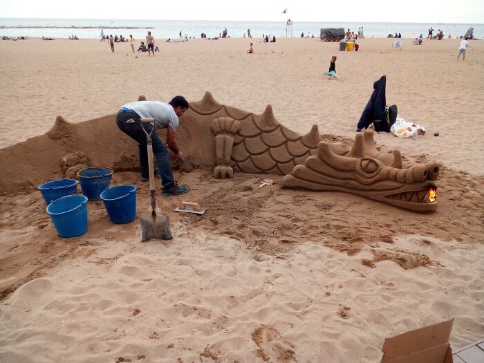 Este tipo en una playa de Barcelona estaba tallando un dragón de arena, y puso una fogata en su boca para que pareciera que respiraba fuego