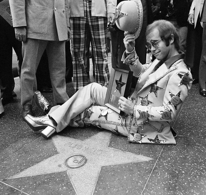 Elton John posando luego de recibir una estrella en el Paseo de la Fama de Hollywood en 1975 (por Jeff Robbins)