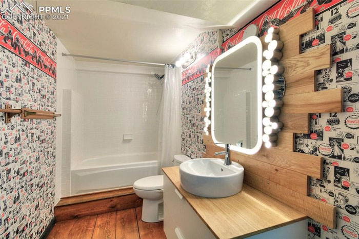 Me burlaré de una casa que acabamos de comprar. Les presento el baño de Coca-Cola. Además, el piso tiene tableros de madera pegados directamente al hormigón. Es un estilo bastante particular… Nada del resto de la casa se parece ni un poco a esto. Es, realmente, una excentricidad