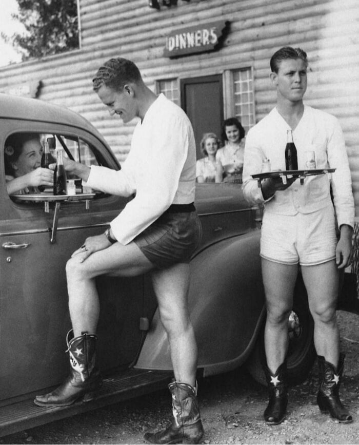 En los años 40, hombres vestidos con pantalones cortos y botas de vaquero servían a las mujeres en un autoservicio de Dallas, Texas 