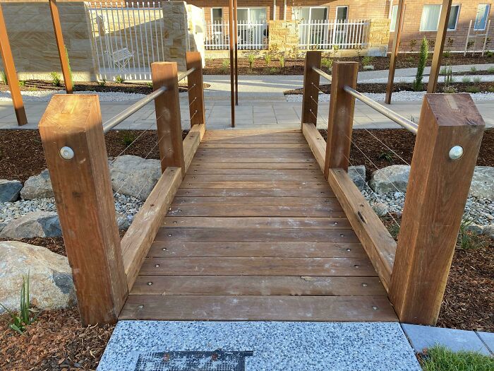 Un hermoso puente de madera dura que construimos en el trabajo. Accesible para sillas de ruedas. Viene con un bonito poste de acero casi en el centro. Esto es lo que pasa cuando los arquitectos se niegan a cambiar su plan incluso cuando el sentido común dice que hay que mover el puente