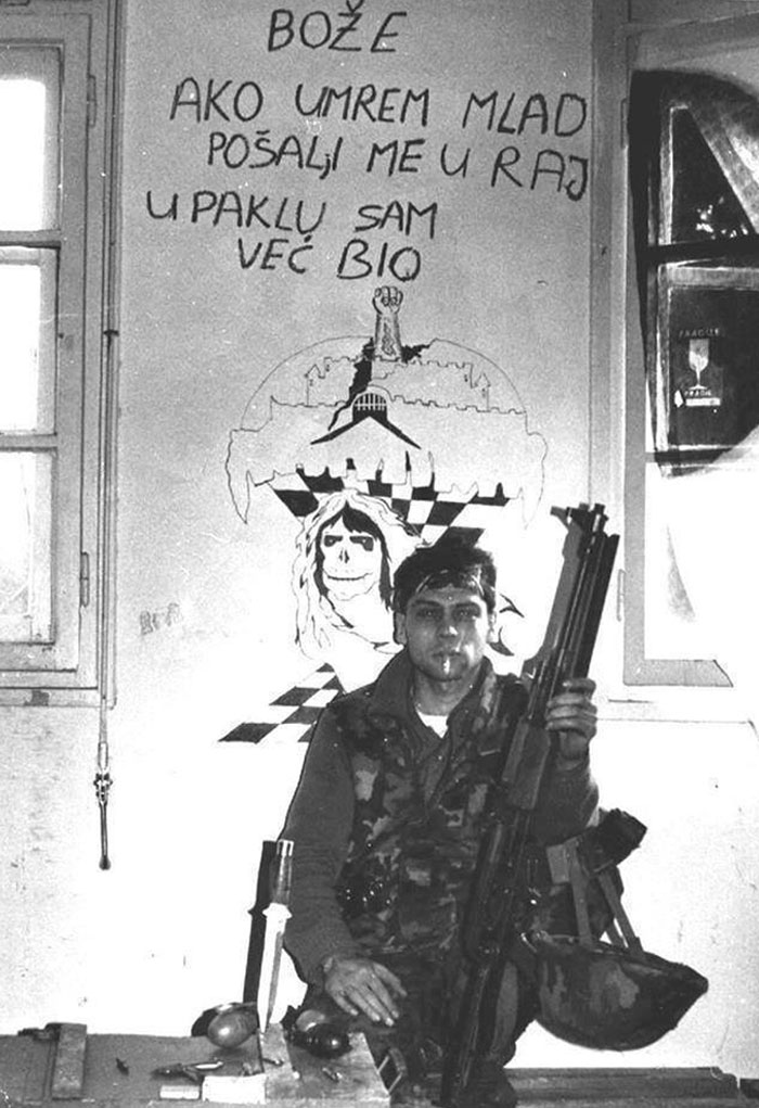 Soldado croata frente a un muro que dice "Dios, si muero joven, mándame al cielo, en el infierno ya he estado"