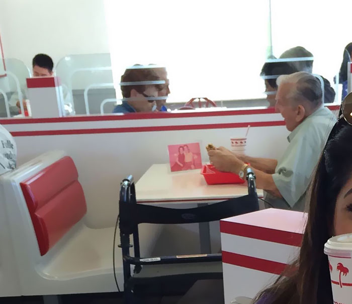 Un anciano comiendo solo en un “In-N-Out” con una foto de su mujer