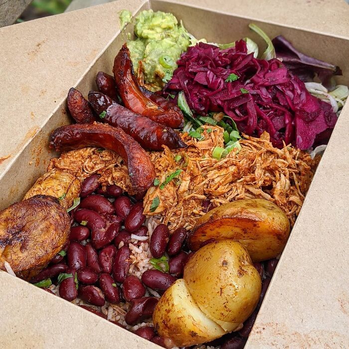Plato colombiano con pollo jalado, chorizo, plátano frito, arroz al ajillo, frijoles rojos, papas y guacamole