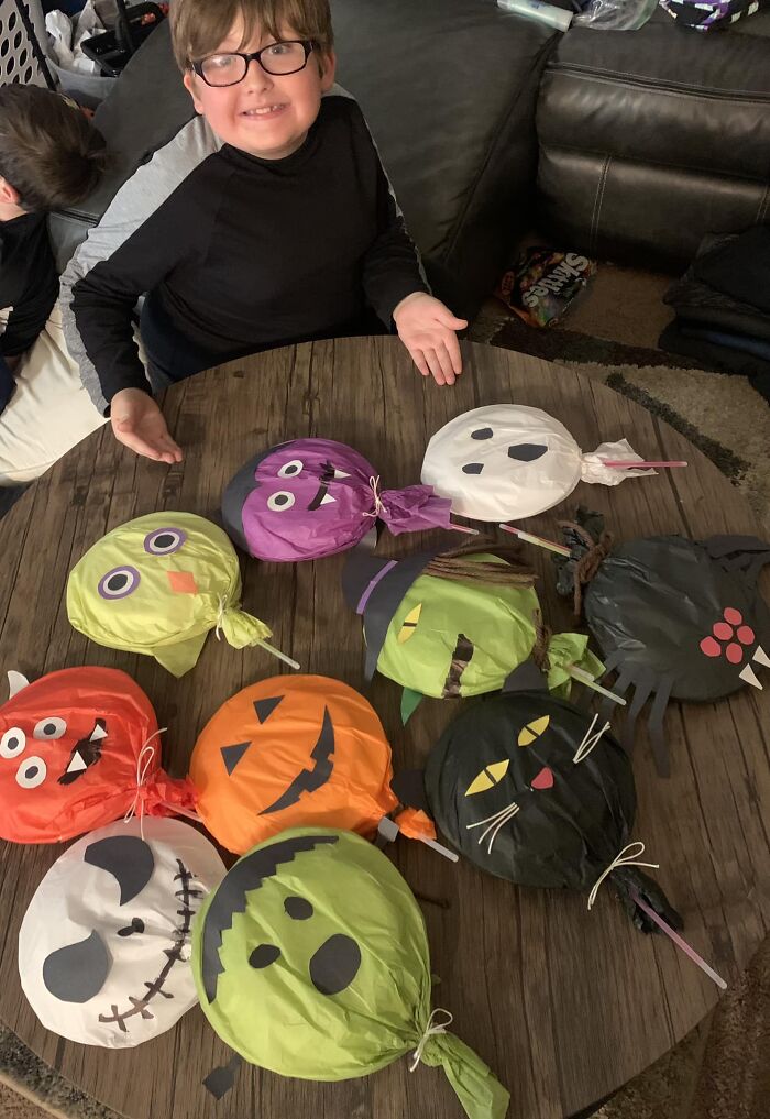 Mi hijo y yo hicimos "paletas" de Halloween para su clase mañana. 2 platos con algunas cosas de caramelo, palos luminosos como el palito, luego papel de seda y cartulina como decoración