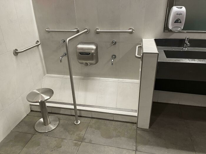 Vi esto en un baño que tiene grifos y drenaje hacia abajo y un secador 