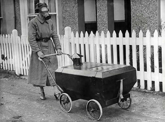 En la foto, una mujer con una máscara antigás y empujando un cochecito de bebé antigás en Inglaterra en 1938