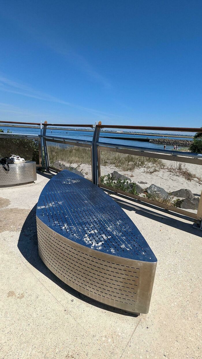 Un banco de acero inoxidable en la playa. La temperatura hoy es de 31°C 