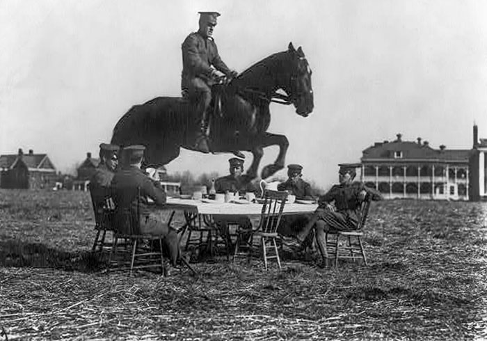 Hombres del ejército de EE.UU. sentados alrededor de la mesa, mientras que uno a caballo salta sobre ella