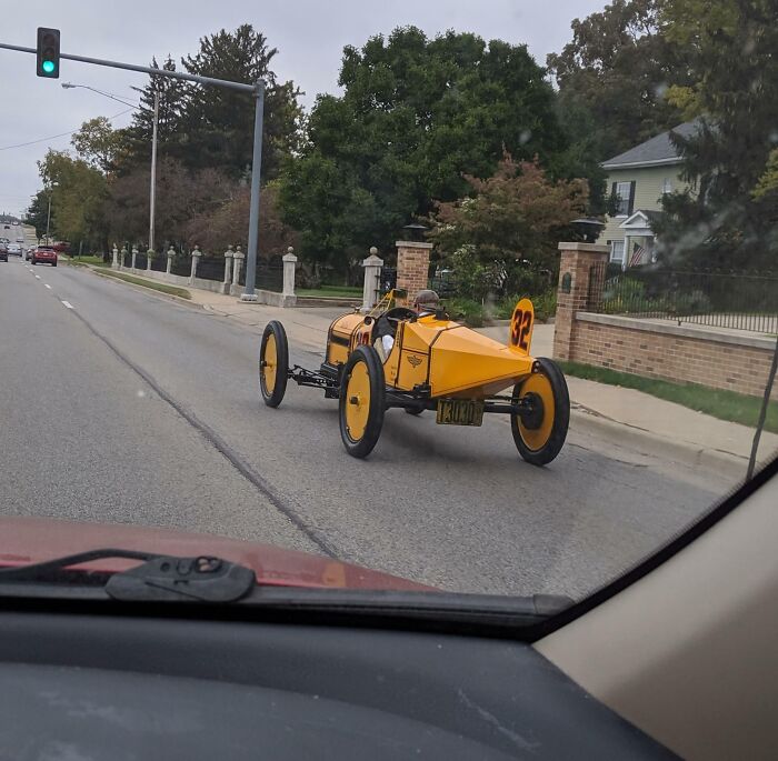 Este tipo conduciendo un coche de carreras de estilo antiguo alrededor de mi ciudad. Tiene la ropa a juego y todo