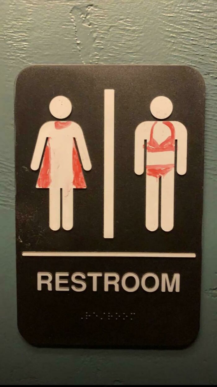Un letrero de baño vandalizado de forma muy moderada, considerando que ha sido pintado con un marcador para pizarra 