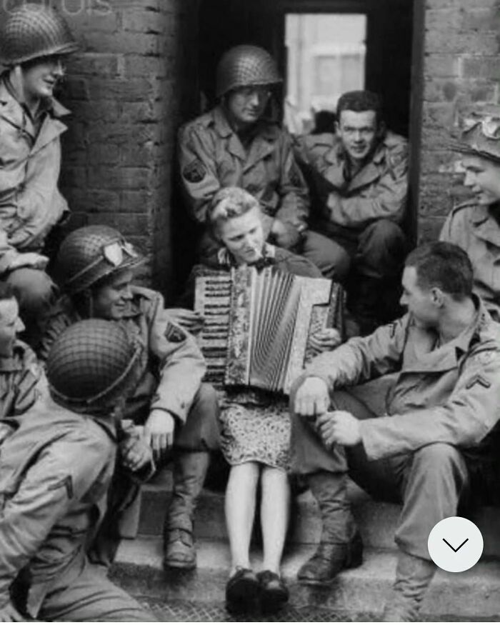 La señora Hale, esposa de un soldado británico, toca el acordeón frente a su casa para un grupo de soldados estadounidenses en Inglaterra, 1944