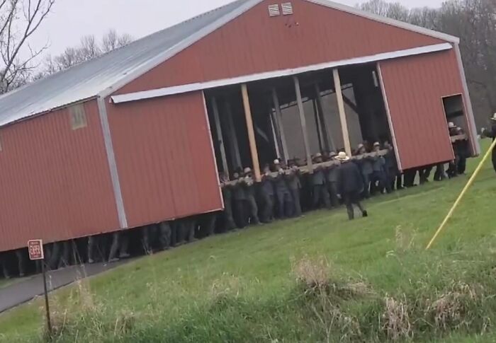 Un montón de amish moviendo un granero
