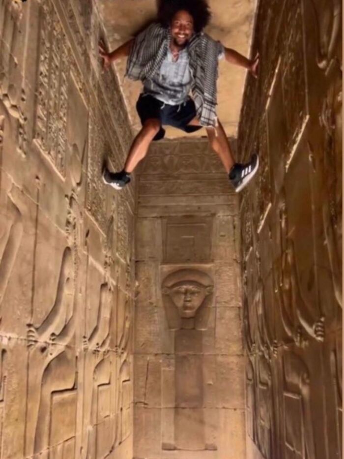 Turista escalando restos arqueológicos del Antiguo Egipto para conseguir visitas