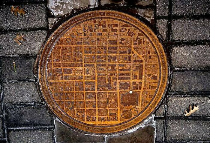 Las tapas de alcantarilla de Oklahoma tienen el mapa de la ciudad y un punto blanco muestra dónde estás
