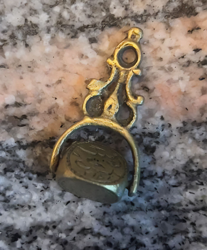 ¿Qué es esta cosa de oro que gira? Mide entre 5 y 7 cm de largo y tiene lo que parecen dibujos en cada lado