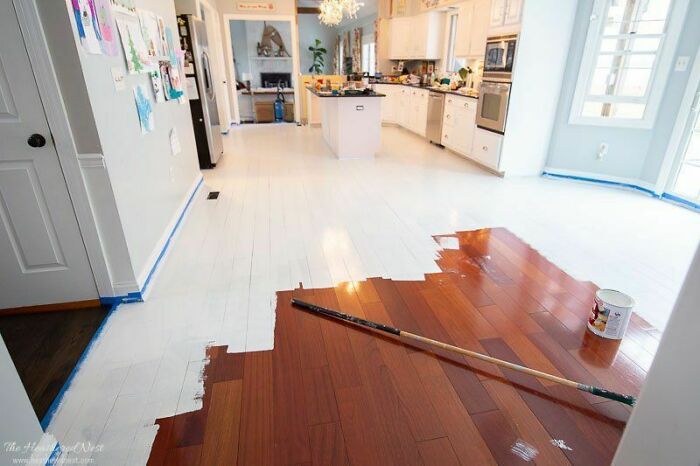 Piso de madera parcialmente pintado de blanco en un proyecto casero fallido durante la renovación del hogar.
