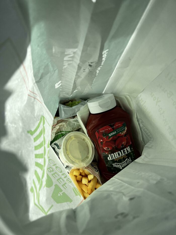 Pedido de comida a domicilio con papas fritas, salsa y condimentos, personas felices por recibir exactamente eso.